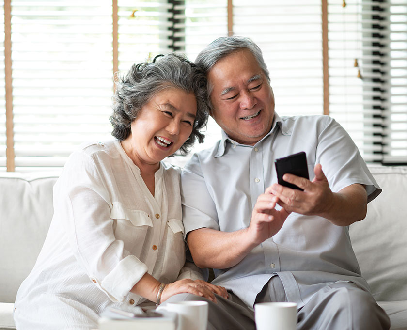 Smiling Asian elderly couple looking at phone